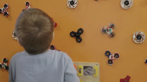 Back view of a child exploring interactive toy wall with spinners Stock Footage 331240422