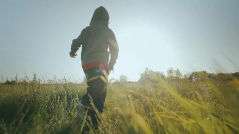 Back view of a child running on the grass in a field on a summer morning Stock Footage 245125839