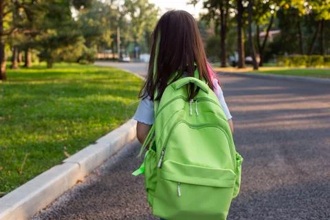 Back view of Child walking to school with green backpack on a sunny day Stock Photos