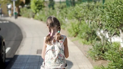 Back view of child walks alone. The girl turns and flap her hand Stock-Footage 106235786