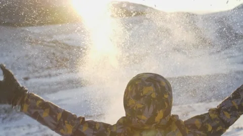 Back view of a child who plays with snow and throws it up with his hands against Stock Footage 151154259
