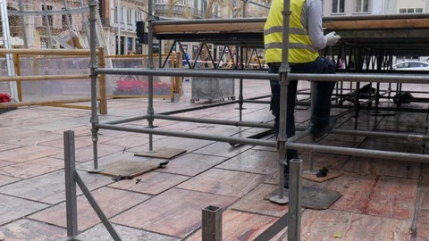 Back view of a city worker with yellow vest assembling a metallic structure Stock Footage 121850391