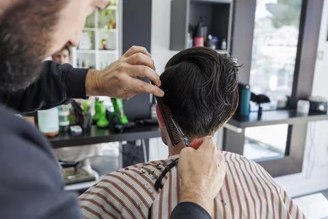 Back View Close Up of Barber Cutting Hair With Scissors and Comb Stock Photos