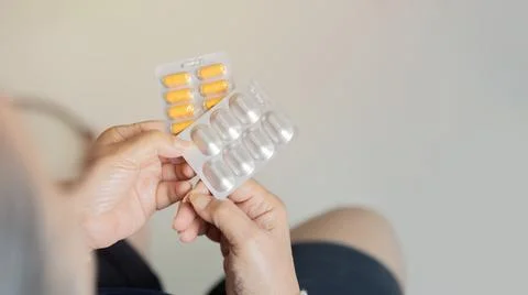 Back view close-up of mature middle-aged woman sitting at home holding pills Stock Photos