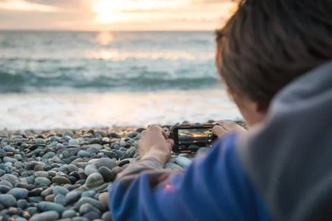 Back view close up young man filming video or taking photo pictures on his Stock Photos