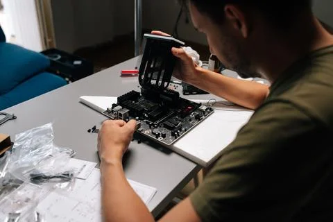 Back view of computer technician male installing CPU cooler onto motherboard Stock Photos