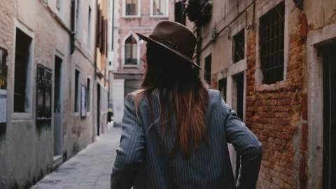 Back view of confident stylish young businesswoman in hat and suit walking along Stock Footage 97186698