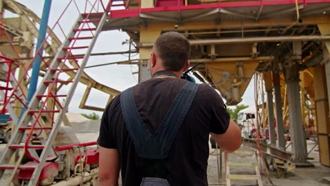 Back view of a construction worker using a walkie-talkie at an industrial site Stock Footage 287248272