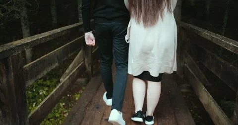 Back view of couple holding hands walking together through the forest. Video stock 130589056