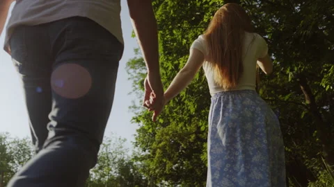 Back view of a couple holding hands and walking together on country field Stock Footage 249513126