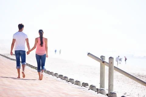Back view, couple holding hands and walk on beach, romantic date and commitment Stock Photos