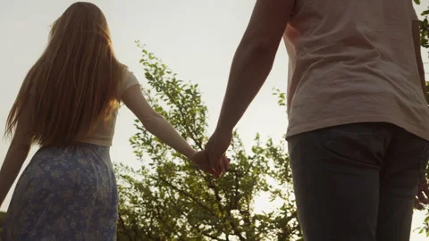 Back view of a couple of lovers holding hands walking in field enjoying outdoor Video stock 256670066