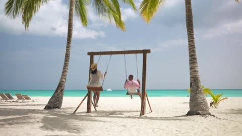 Back view of couple playing on a swing between palm trees on tropical beach Stock Footage 244926070