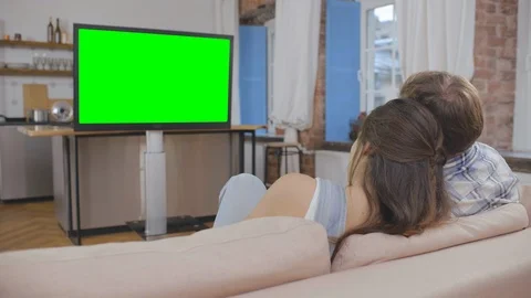 Back view of couple resting in apartment, sitting on sofa together and watching Stock Footage 124848458