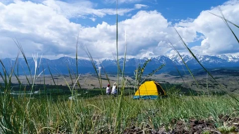 Back view of couple tourists covered with a plaid sitting on a hill near the Stock Footage 77891102