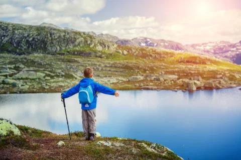 Back view of cute boy with hiking equipment in the mountains Фото