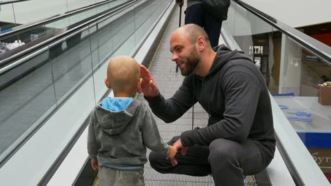 Back view of dad and his little son riding escalator in a shopping center Video stock 92936686