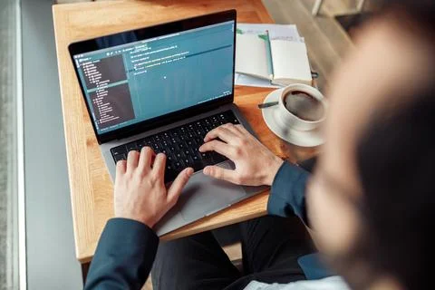 Back view of developer programmer freelancer working on project in cafe. Blurred Stock Photos