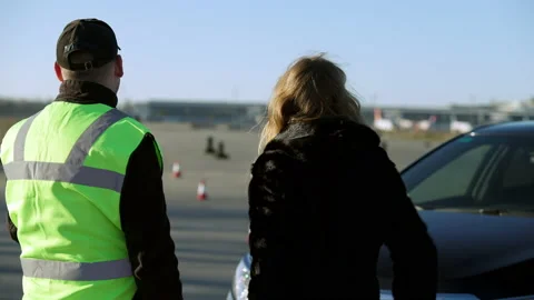 Back view of driving instructor and female student talking outdoors on sunny day Stock Footage 148749732