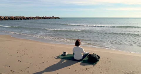 Back view with drone of middle aged woman sitting reflecting in front of the sun Stock Footage 147406792