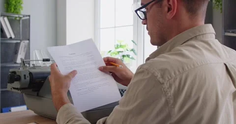 Back view editor proofreading document beside vintage typewriter in home office Video stock 322509683