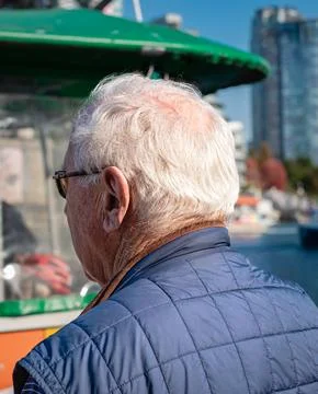 Back view of an elderly man with short gray hair while standing outdoors. Age Stock Photos