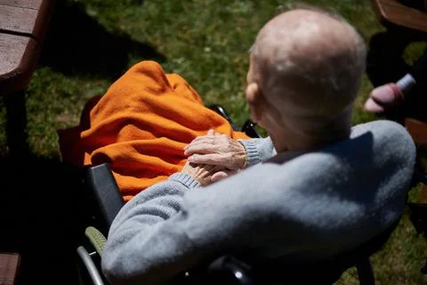 Back view of an elderly man sitting in a wheelchair with a bright orange blan Fotos Stock