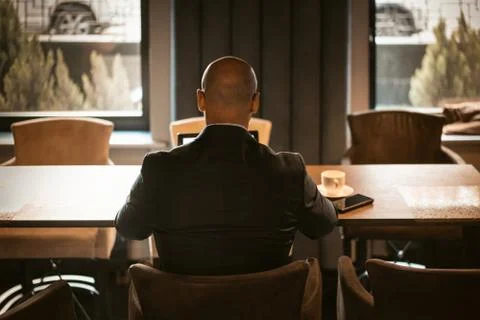 Back view of elegant CEO dressed in expensive suit sitting at the table in the Stock Photos
