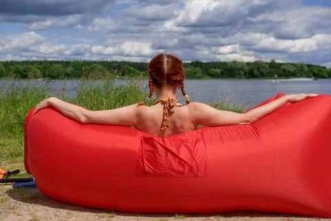 Back view of elegant lady in bikini relaxing on a chaise lounge, sandy beach Stock Photos
