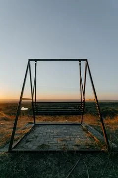 Back view of an empty metallic swing. summer sunset Stock Photos
