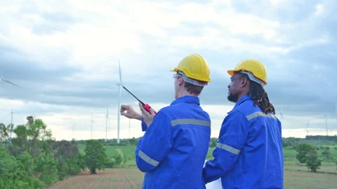 Back view of engineer and technician looking at wind turbines Stock Footage 254003651