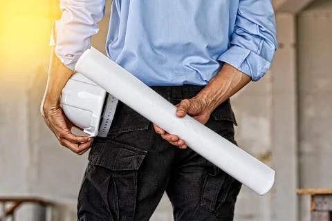 Back view of engineer holding blue print and white helmet Stock Photos