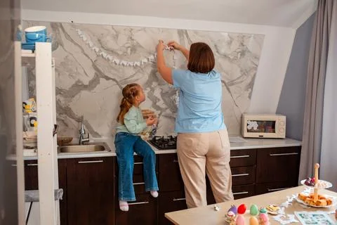 Back view of family decorating kitchen for Easter celebrations with paper gar Foto stock