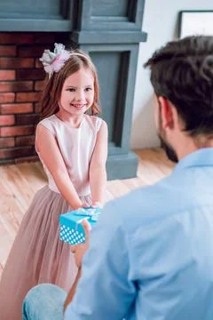 Back view of father giving present box to his smiling daughter at home Stock Photos
