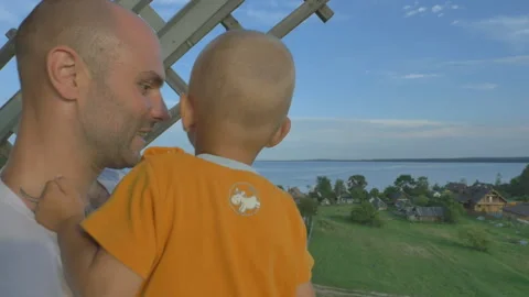 Back view of father holding son on hands on the balcony Видео 155392299