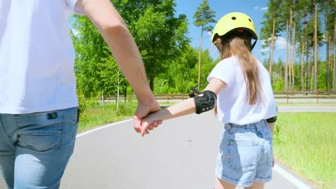 Back view father walking on street and supporting little daughter while she lear Stock Footage 279656326