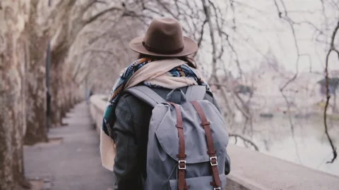Back view of female freelancer with backpack walking along autumn Tiber river Video stock 94977810