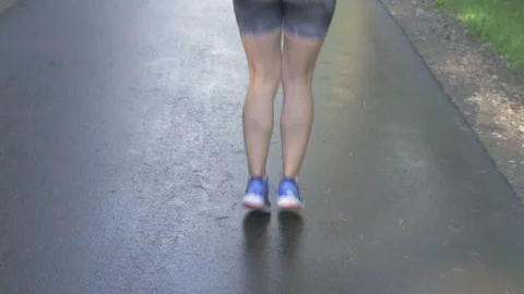 Back view of female jumping through skipping rope outside. Stock Footage 132621123