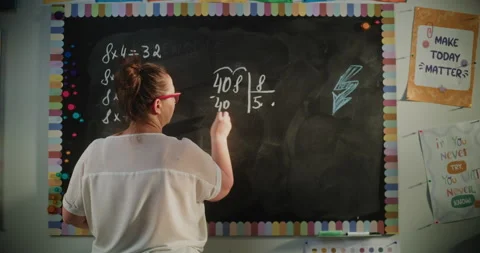 Back View of Female Teacher Writing on the Chalkboard, Explaining Multiplication Stock Footage 313736464