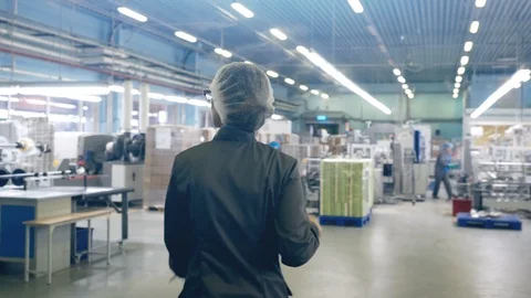 Back view of female worker in printing house, walking through equipment Video stock 106635752