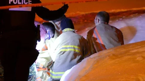 Back view of firemen performing CPR on hidden victim in the snow Stock Footage 89414483