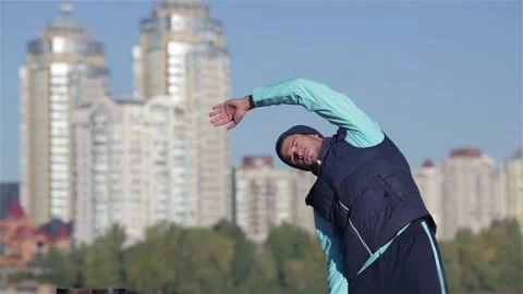 Back view of fit men stretches muscles before morning jog outdoors Stock Footage 252675693