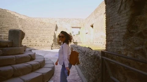 Back view of fit stylish young brunette woman walking down the ruins of ancient 스톡 동영상 108776454