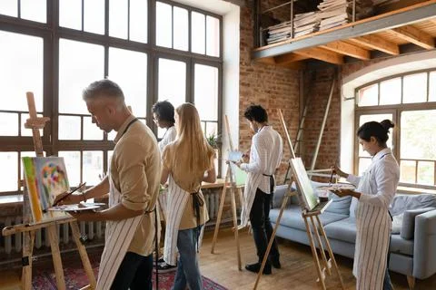 Back view five young multiethnic painters engaged in group art-class Stock Photos