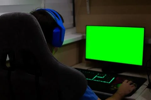Back view of gamer in computer chair wearing bright headphones in front of a  Stock Photos