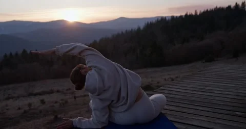 Back view of girl doing stretching and yoga on blue gym mat while watching Vídeos de archivo 313380233