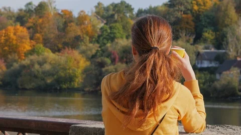 Back view of girl drinking coffee from paper cup and talking on phone. Stock Footage 119149973