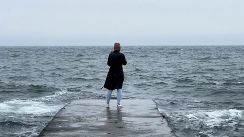 Back view of girl standing alone on pier near the sea in a storm. Woman standing Stock Footage 238945346