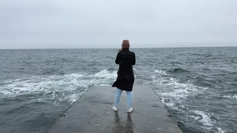 Back view of girl standing alone on pier near the sea in a storm. Woman standing Stock Footage 238945375