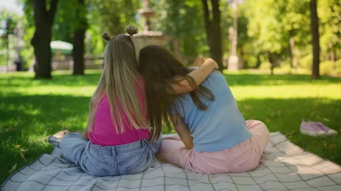 Back view of girl supporting and hugging her friend on park lawn, togetherness Vídeo Stock 319828867